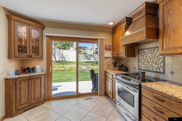 918 N 150th St, Omaha, NE 68154 - kitchen featuring stainless steel electric range, custom exhaust hood, brown cabinets, and light tile patterned floors