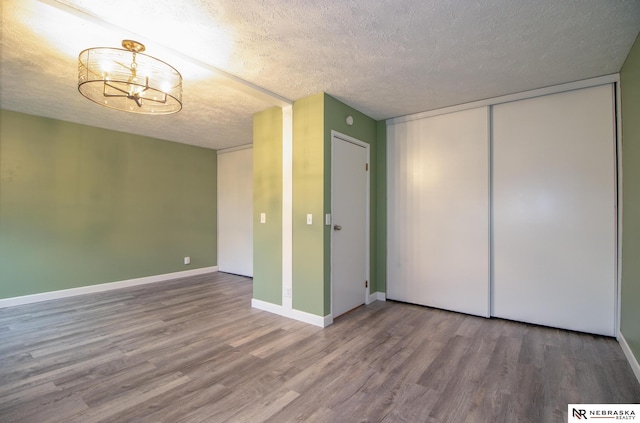 13220 Carpenter St, Omaha, NE 68138 - unfurnished bedroom with wood finished floors, a chandelier, a textured ceiling, baseboards, and a closet