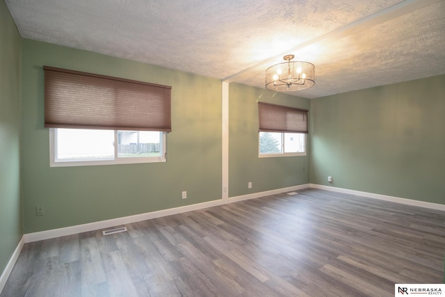 13220 Carpenter St, Omaha, NE 68138 - unfurnished room with a chandelier, a textured ceiling, wood finished floors, and baseboards