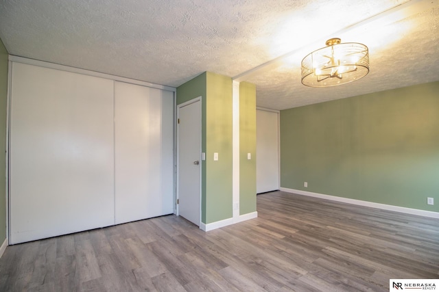 13220 Carpenter St, Omaha, NE 68138 - spare room featuring a textured ceiling, wood finished floors, a chandelier, and baseboards