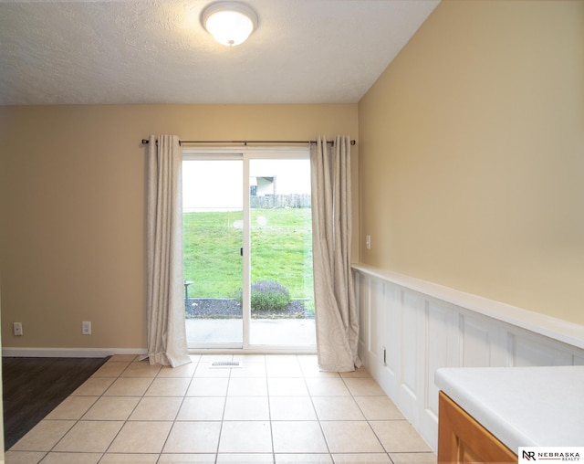 13220 Carpenter St, Omaha, NE 68138 - unfurnished dining area with wainscoting, a textured ceiling, and light tile patterned floors