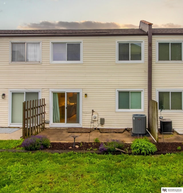 13220 Carpenter St, Omaha, NE 68138 - back of house at dusk with cooling unit, a yard, and a patio