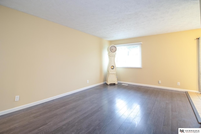 13220 Carpenter St, Omaha, NE 68138 - empty room with a textured ceiling, dark wood-type flooring, and baseboards
