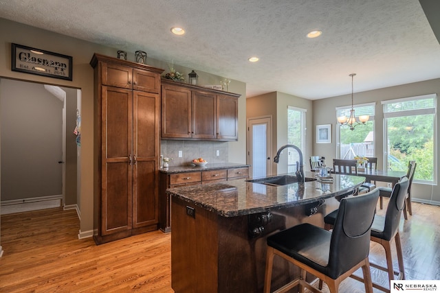 21313 Castlerock Ln, Gretna, NE 68028 - kitchen featuring a sink, a textured ceiling, light wood-style floors, baseboards, and a breakfast bar area