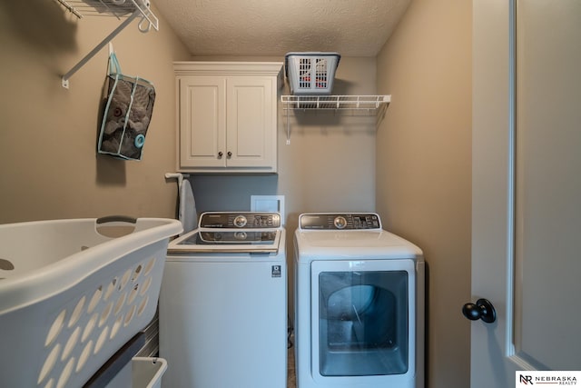 21313 Castlerock Ln, Gretna, NE 68028 - laundry room featuring washing machine and clothes dryer, cabinet space, and a textured ceiling