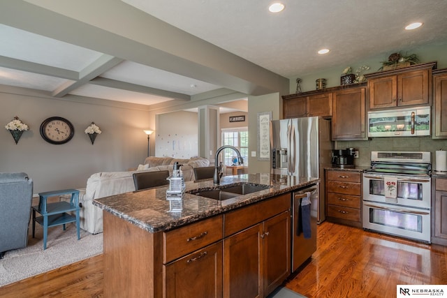 21313 Castlerock Ln, Gretna, NE 68028 - kitchen with stainless steel appliances, a sink, open floor plan, dark stone counters, and an island with sink