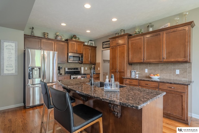 21313 Castlerock Ln, Gretna, NE 68028 - kitchen with appliances with stainless steel finishes, brown cabinets, baseboards, an island with sink, and recessed lighting