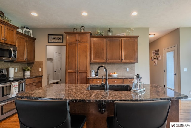 21313 Castlerock Ln, Gretna, NE 68028 - kitchen featuring stainless steel appliances, light wood-type flooring, brown cabinetry, a sink, and recessed lighting