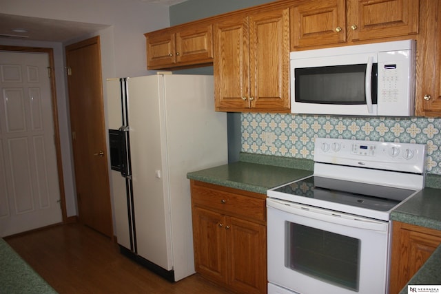 120 W Deer Ln, Plattsmouth, NE 68048 - kitchen with white appliances, brown cabinetry, dark countertops, and decorative backsplash