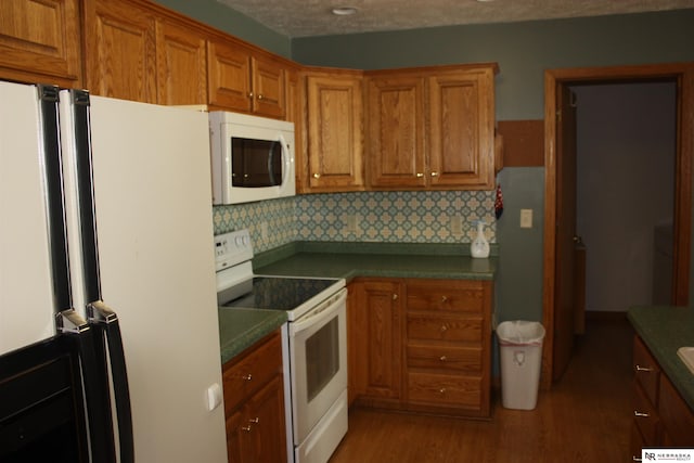 120 W Deer Ln, Plattsmouth, NE 68048 - kitchen featuring white appliances, brown cabinets, light wood-style floors, tasteful backsplash, and dark countertops