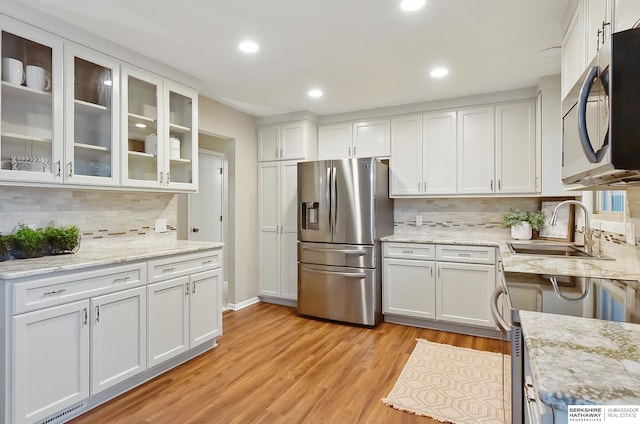 2615 Jack Pine St, Bellevue, NE 68123 - kitchen with appliances with stainless steel finishes, a sink, white cabinets, decorative backsplash, and light wood-style flooring