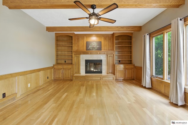 10428 Monroe St, Omaha, NE 68127 - unfurnished living room with light wood-type flooring, built in shelves, wainscoting, a high end fireplace, and a ceiling fan