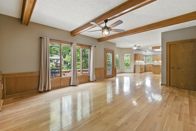 10428 Monroe St, Omaha, NE 68127 - unfurnished living room with a ceiling fan, beamed ceiling, light wood finished floors, and a wainscoted wall