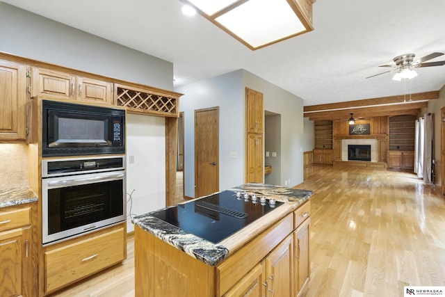 10428 Monroe St, Omaha, NE 68127 - kitchen featuring black appliances, ceiling fan, light wood-style flooring, open floor plan, and a center island