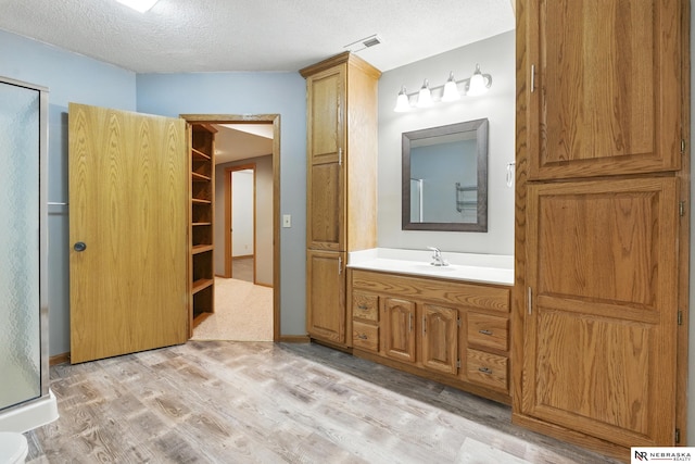 10428 Monroe St, Omaha, NE 68127 - full bath featuring wood finished floors, vanity, a textured ceiling, and a stall shower