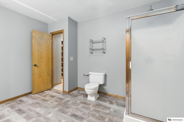 10428 Monroe St, Omaha, NE 68127 - bathroom featuring wood finished floors, a stall shower, toilet, baseboards, and a textured ceiling