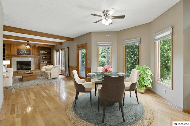 10428 Monroe St, Omaha, NE 68127 - dining space featuring a ceiling fan, beam ceiling, a glass covered fireplace, light wood-style floors, and baseboards