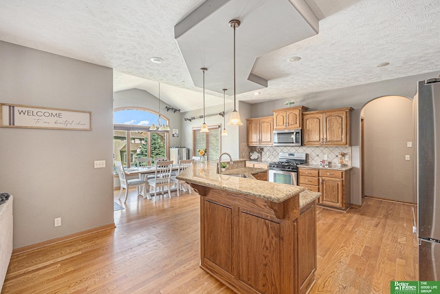 2231 Crystal Creek Dr, Papillion, NE 68046 - kitchen featuring appliances with stainless steel finishes, arched walkways, a sink, light stone countertops, and light wood finished floors