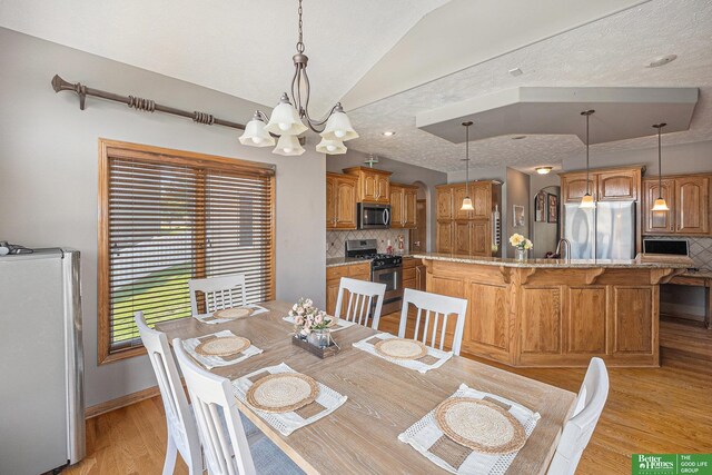 2231 Crystal Creek Dr, Papillion, NE 68046 - dining area with vaulted ceiling, a chandelier, light wood-type flooring, and baseboards