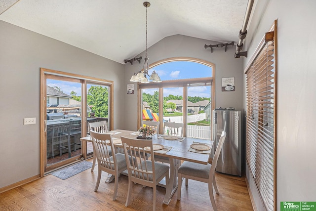 2231 Crystal Creek Dr, Papillion, NE 68046 - dining area with lofted ceiling, light wood-style flooring, a chandelier, and baseboards