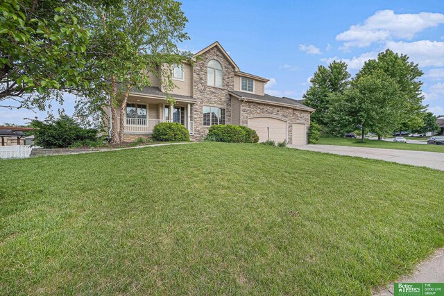 2231 Crystal Creek Dr, Papillion, NE 68046 - traditional home with stone siding, a porch, concrete driveway, and a front yard