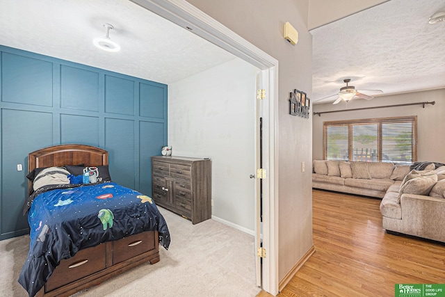 2231 Crystal Creek Dr, Papillion, NE 68046 - bedroom with a ceiling fan, a decorative wall, a textured ceiling, and light wood-style floors