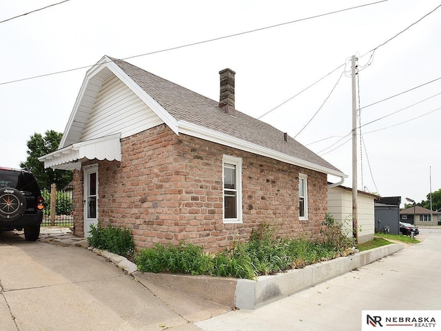4540 S 41st St, Omaha, NE 68107 - view of home's exterior with stone siding, a chimney, and roof with shingles