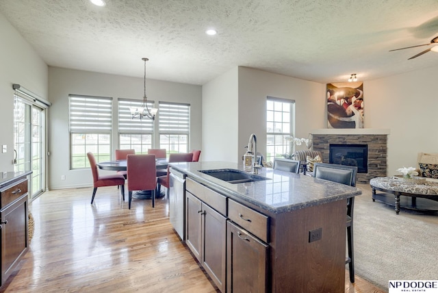 15930 Grebe St, Bennington, NE 68007 - kitchen with a sink, dishwasher, a textured ceiling, a stone fireplace, and light wood-style floors