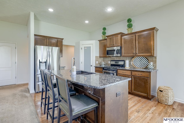 15930 Grebe St, Bennington, NE 68007 - kitchen featuring appliances with stainless steel finishes, a sink, a kitchen island with sink, a kitchen breakfast bar, and decorative backsplash