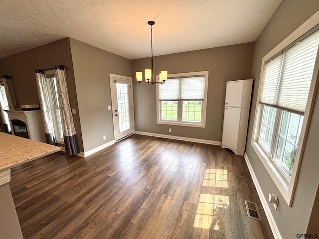 221 Briarwood Ln, Seward, NE 68434 - unfurnished dining area featuring a chandelier, dark wood-style floors, baseboards, a glass covered fireplace, and a textured ceiling