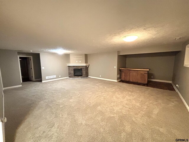221 Briarwood Ln, Seward, NE 68434 - unfurnished living room with a bar, a fireplace, baseboards, carpet flooring, and a textured ceiling