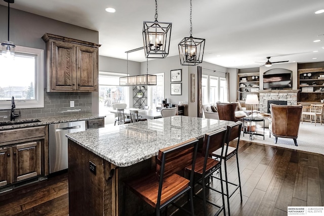 1809 S 220th Ave, Omaha, NE 68022 - kitchen featuring a ceiling fan, stainless steel dishwasher, a stone fireplace, dark wood finished floors, and light stone countertops