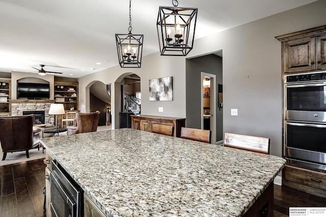 1809 S 220th Ave, Omaha, NE 68022 - kitchen with appliances with stainless steel finishes, arched walkways, ceiling fan, a stone fireplace, and light stone counters