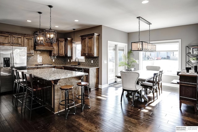 1809 S 220th Ave, Omaha, NE 68022 - kitchen featuring stainless steel appliances, a center island, tasteful backsplash, a kitchen breakfast bar, and light stone counters