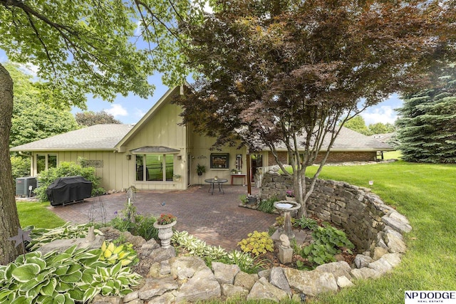 2723 Eagle Dr, Fremont, NE 68028 - rear view of house with a patio area, a lawn, central AC, a shingled roof, and board and batten siding