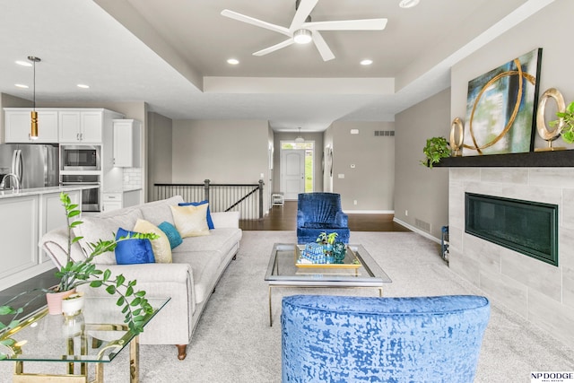 15301 Kansas Ave, Omaha, NE 68116 - living area featuring ceiling fan, a tray ceiling, recessed lighting, a tiled fireplace, and baseboards