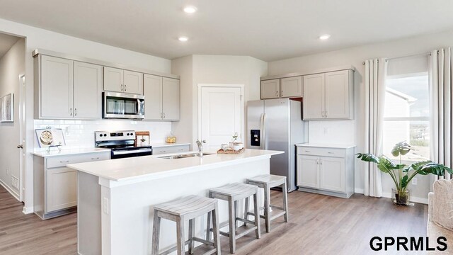 8520 S 179th St, Omaha, NE 68137 - kitchen with stainless steel appliances, a sink, light wood-style floors, a breakfast bar, and decorative backsplash