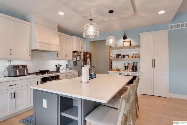 11511 S 190th St, Gretna, NE 68028 - kitchen featuring open shelves, appliances with stainless steel finishes, decorative backsplash, a kitchen island with sink, and light wood finished floors
