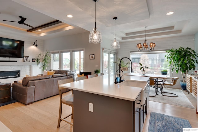 11511 S 190th St, Gretna, NE 68028 - kitchen featuring a raised ceiling, a stone fireplace, light countertops, light wood-style floors, and recessed lighting