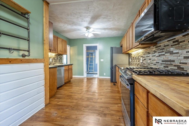 610 S 10th St, Plattsmouth, NE 68048 - kitchen with stainless steel appliances, ceiling fan, brown cabinets, decorative backsplash, and wood finished floors