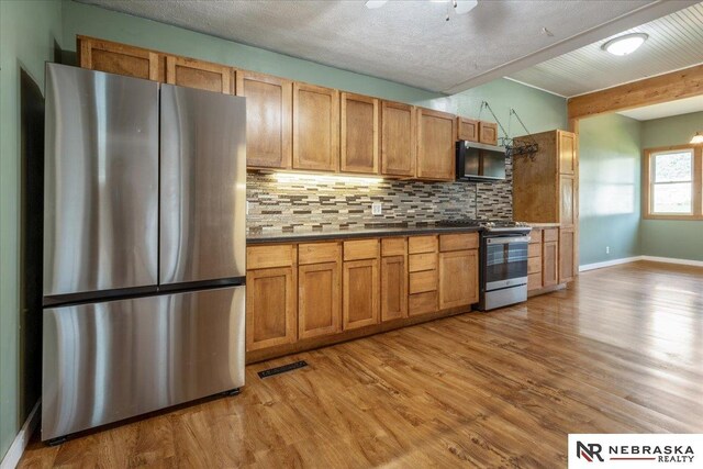 610 S 10th St, Plattsmouth, NE 68048 - kitchen with appliances with stainless steel finishes, tasteful backsplash, light wood-style flooring, beamed ceiling, and dark countertops