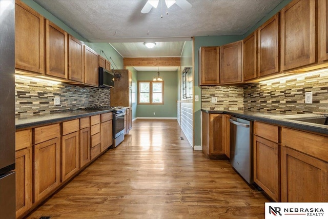 610 S 10th St, Plattsmouth, NE 68048 - kitchen featuring appliances with stainless steel finishes, dark countertops, wood finished floors, decorative backsplash, and a textured ceiling