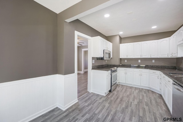 2945 N 59th St, Omaha, NE 68104 - kitchen featuring stainless steel appliances, light wood-type flooring, white cabinets, wainscoting, and dark stone countertops