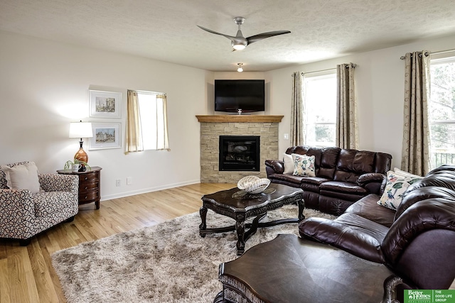 2627 N 166th St, Omaha, NE 68116 - living room featuring a ceiling fan, wood finished floors, a fireplace, a textured ceiling, and baseboards