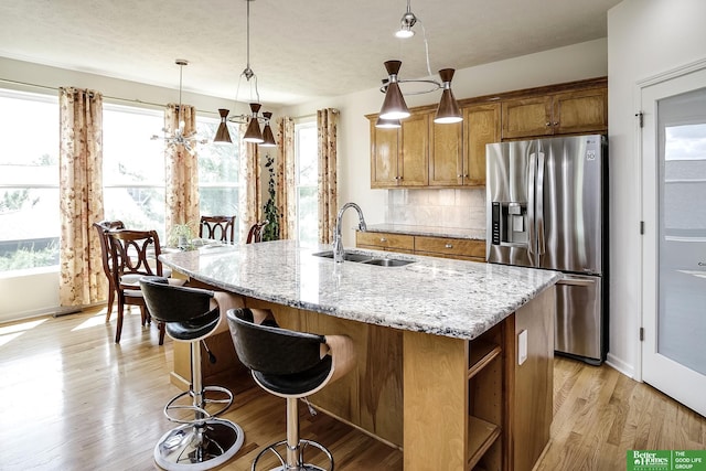 2627 N 166th St, Omaha, NE 68116 - kitchen featuring stainless steel refrigerator with ice dispenser, a sink, brown cabinets, backsplash, and light stone countertops