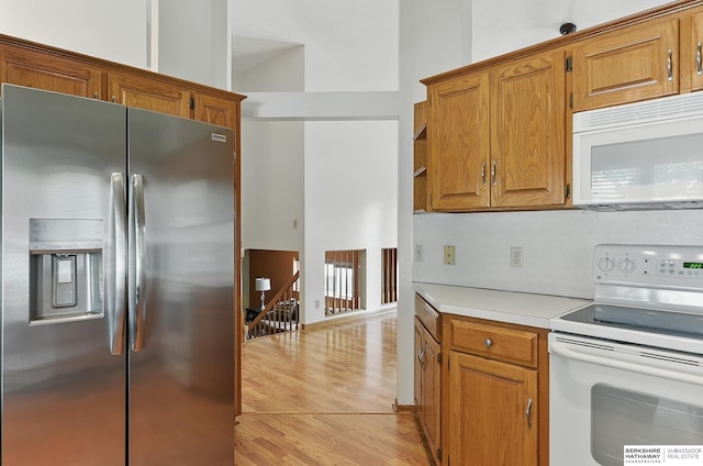 12335 Wirt St, Omaha, NE 68164 - kitchen featuring white appliances, light wood-type flooring, light countertops, brown cabinets, and lofted ceiling