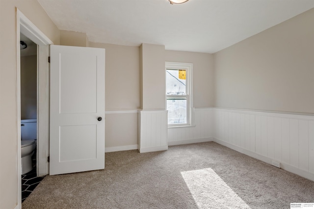 1444 S 16th St, Omaha, NE 68108 - unfurnished bedroom featuring a wainscoted wall and carpet floors