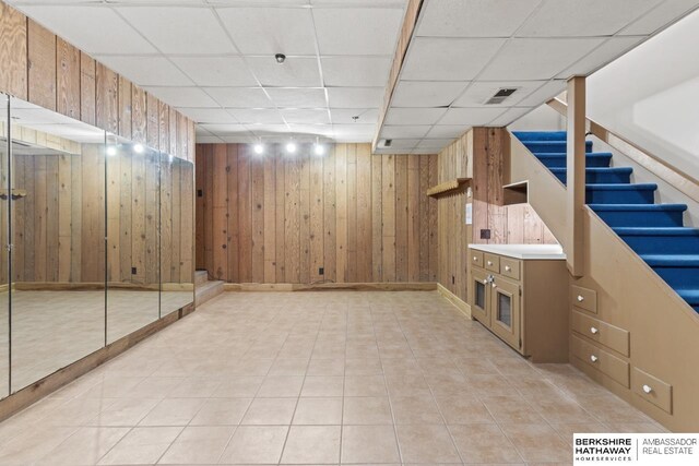 17409 Webster Blvd, Plattsmouth, NE 68048 - finished below grade area featuring wooden walls, a drop ceiling, stairway, light tile patterned floors, and baseboards