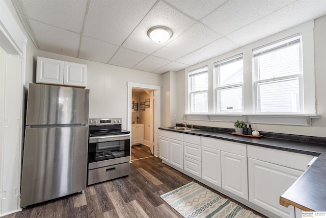 4328 Burdette St, Omaha, NE 68111 - kitchen with appliances with stainless steel finishes, a drop ceiling, dark countertops, white cabinets, and dark wood-style flooring