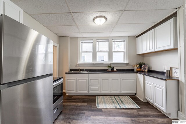4328 Burdette St, Omaha, NE 68111 - kitchen with stainless steel appliances, a paneled ceiling, dark countertops, a sink, and dark wood-style flooring